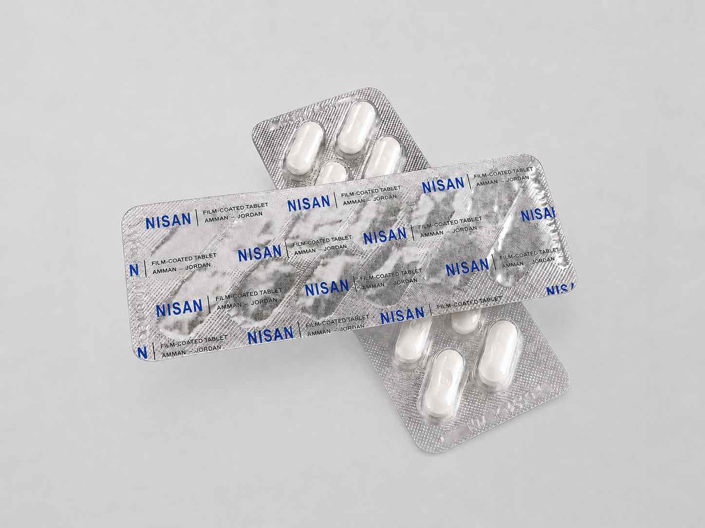 Two NISAN-printed aluminium blister packs, one foil-side up showing the printed design and one showing sealed white tablets