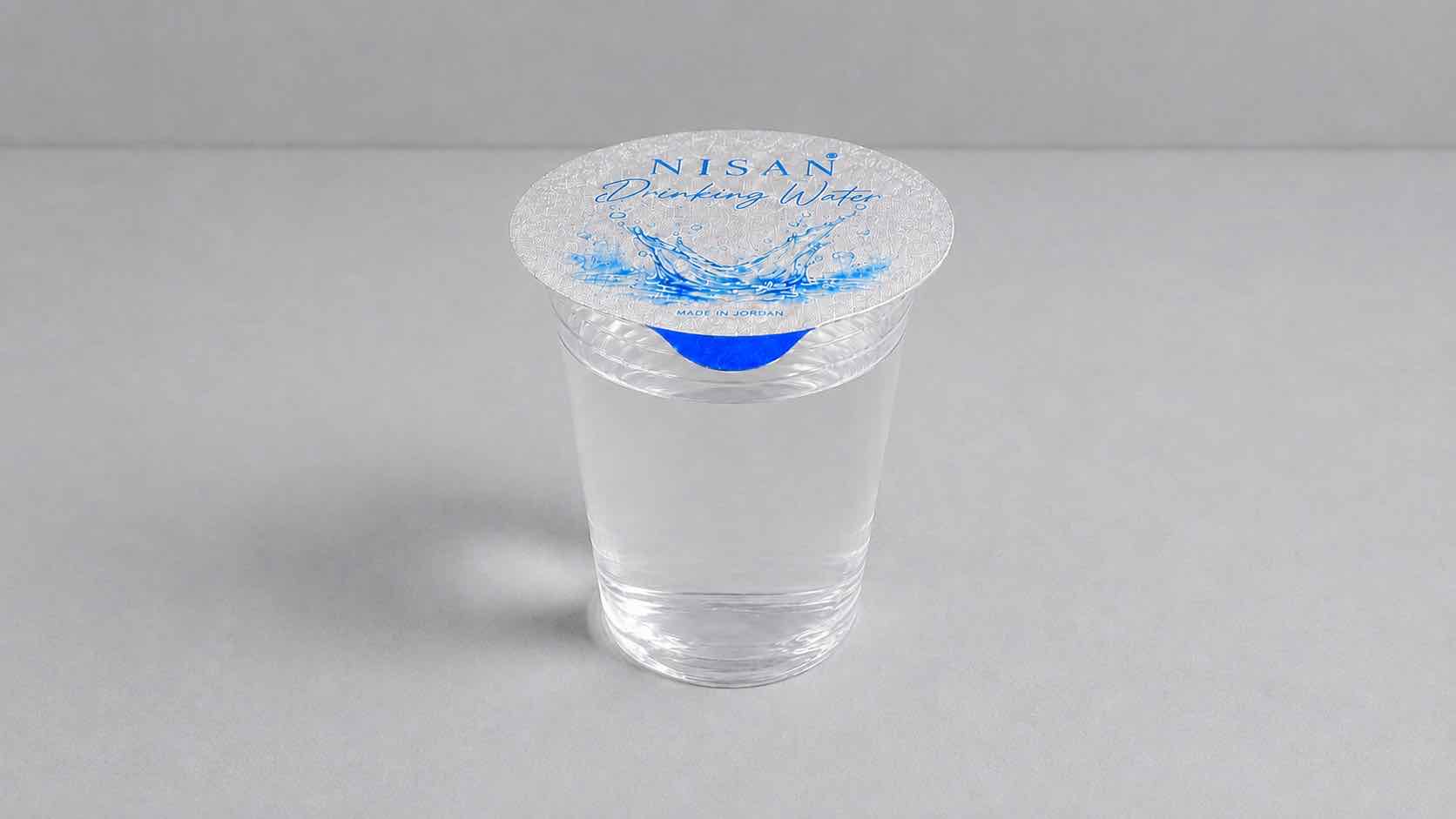 Embossed aluminium foil lid sealed on a NISAN-branded clear drinking-water cup
